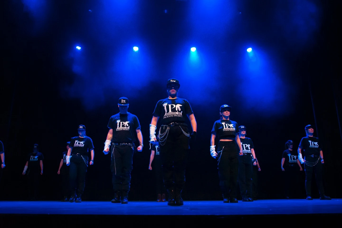 Bailarines con camisetas de Jackson Project en una escena iluminada en azul