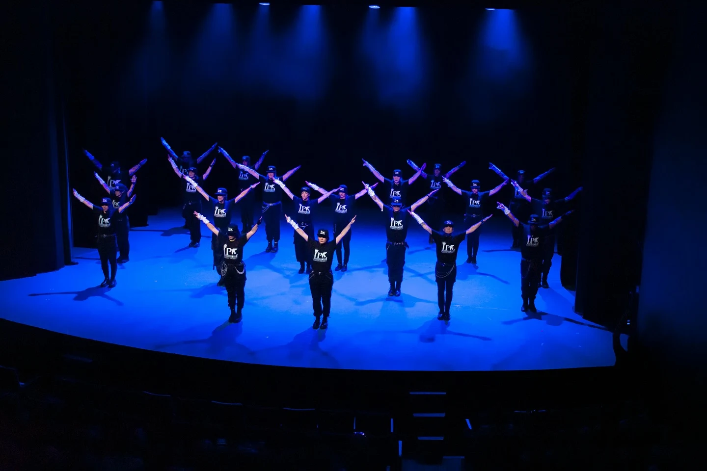 La compañía forma una coreografía sincronizada con los brazos extendidos bajo luces azules